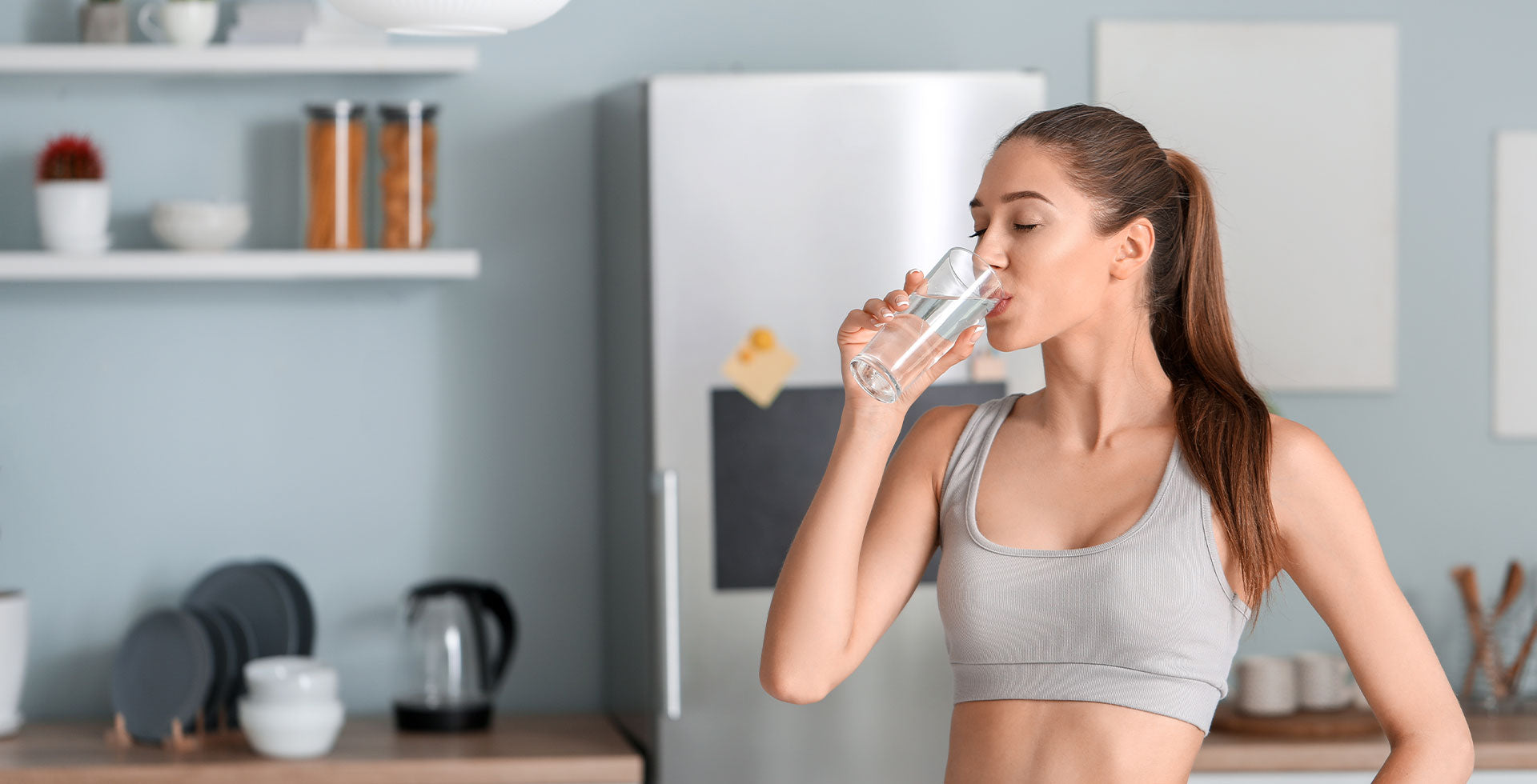 Woman drinking water in a kitchen setting